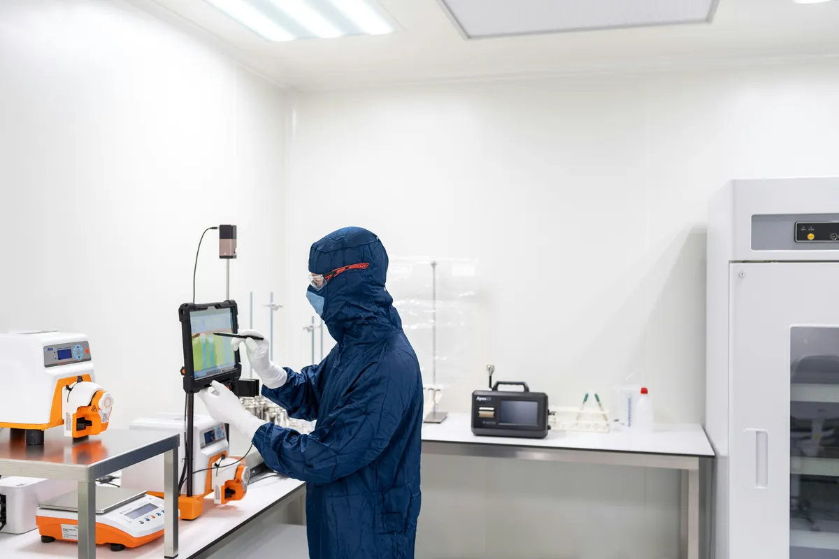 Operator in protective clothing working at a touchscreen terminal in the cleanroom